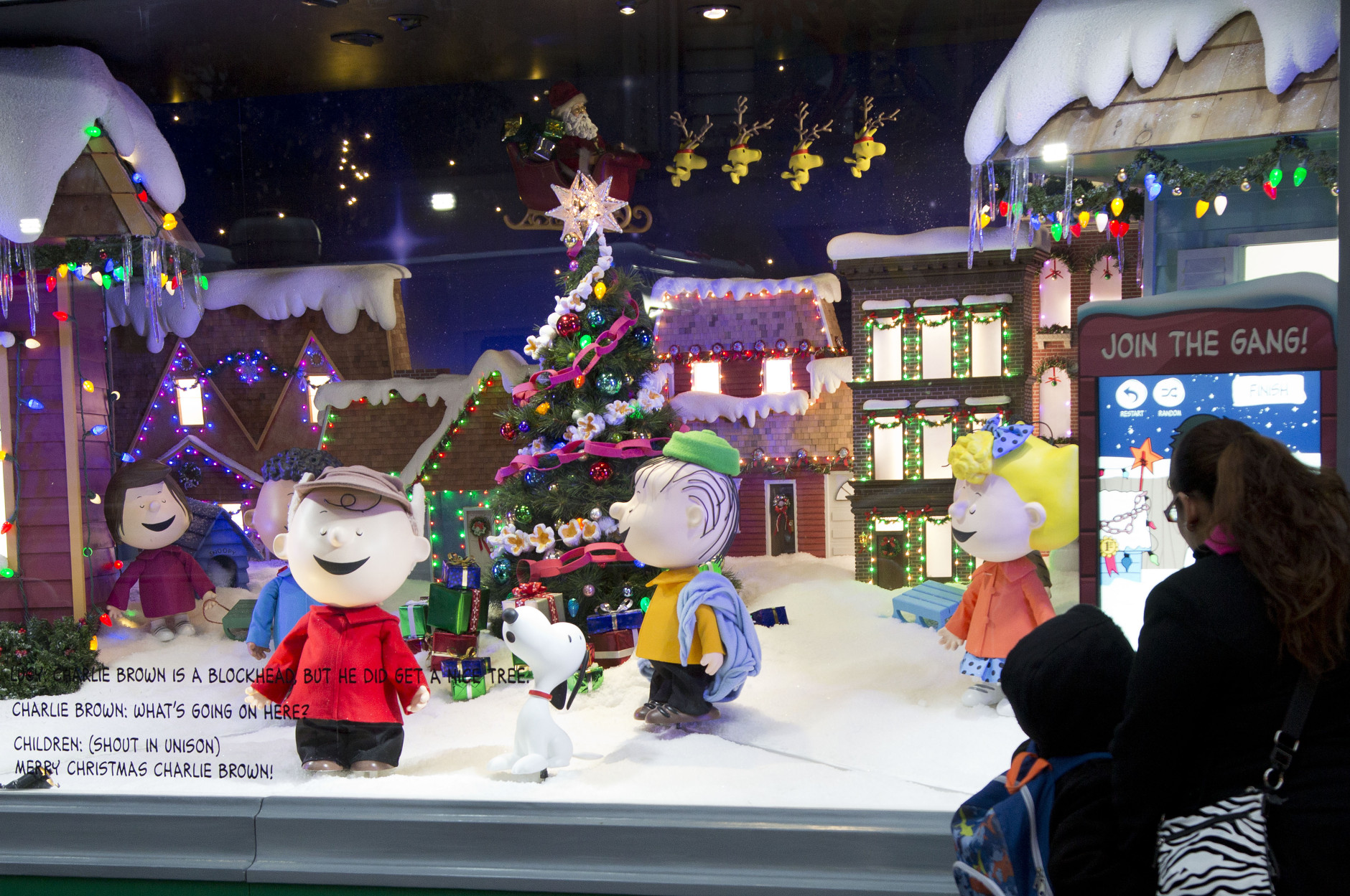 People stop to look at Peanuts characters displayed in a holiday window at Macy's, Tuesday, Nov. 24, 2015 in New York. (AP Photo/Mark Lennihan)