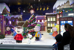 People stop to look at Peanuts characters displayed in a holiday window at Macy's, Tuesday, Nov. 24, 2015 in New York. (AP Photo/Mark Lennihan)