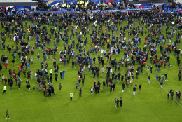 Spectators invade the pitch of the Stade de France stadium after the international friendly soccer France against Germany, Friday, Nov. 13, 2015 in Saint Denis, outside Paris. At least 35 people were killed in shootings and explosions around Paris, many of them in a popular theater where patrons were taken hostage, police and medical officials said Friday.  Two explosions were heard outside the Stade de France stadium. (AP Photo/Michel Euler)