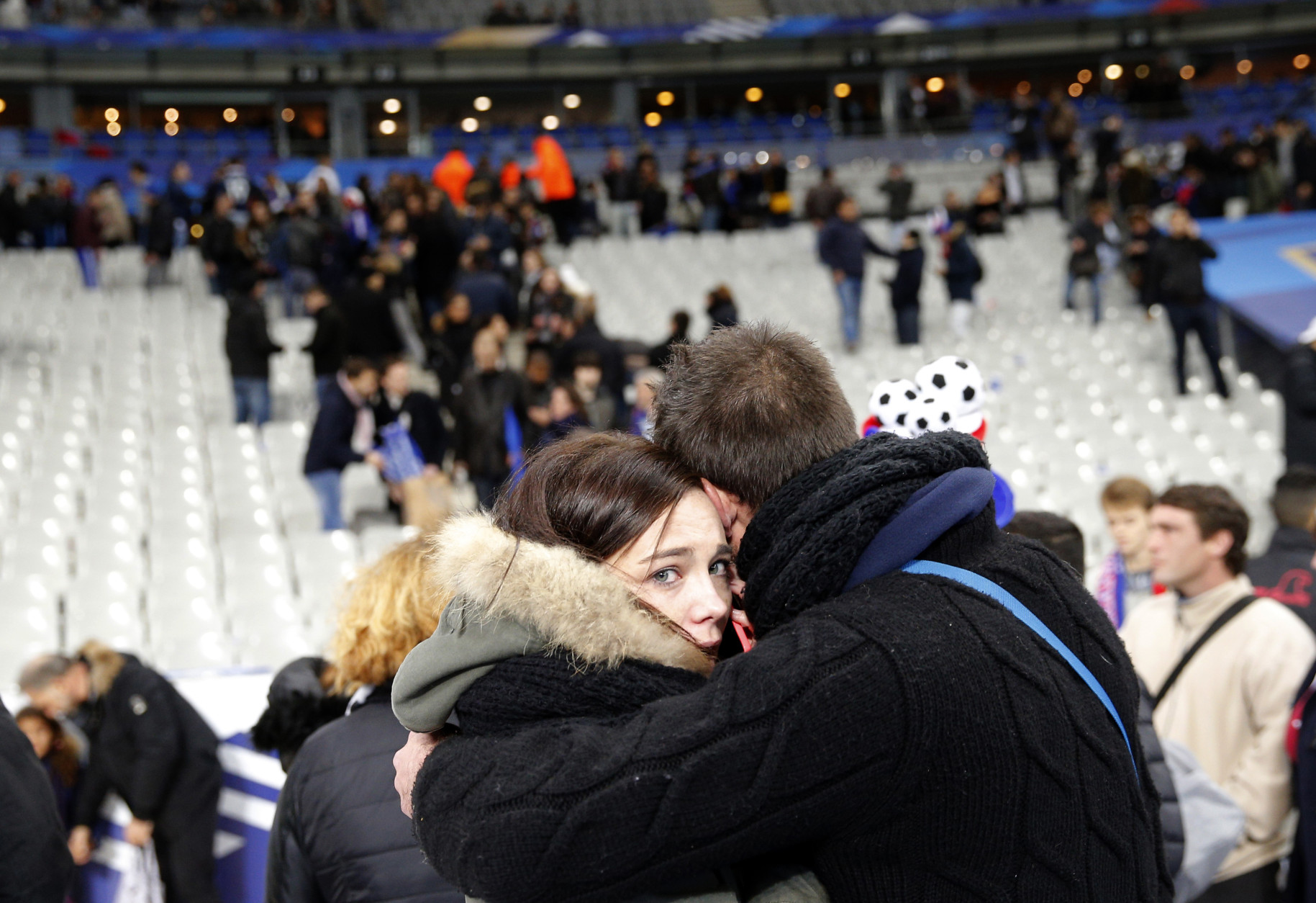 Spectators embrace each other as they stand on the playing field of the Stade de France stadium at the end of a friendly soccer match between France and Germany in Saint Denis, outside Paris, Friday, Nov. 13, 2015. Hundreds made their way to the pitch after explosions were heard nearby. Multiple fatal attacks throughout the city have prompted President Francois Hollande to announce he was closing the country's borders and declaring a state of emergency. (AP Photo/Christophe Ena)