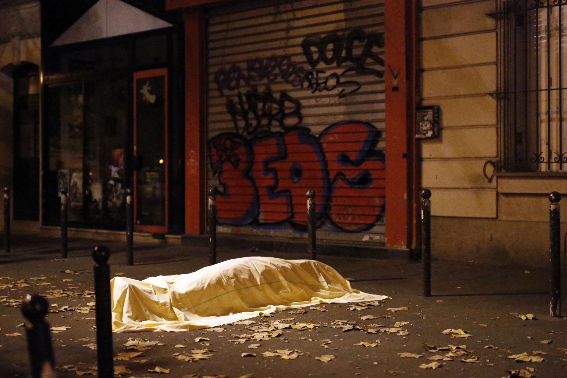 A victim under a blanket lays dead outside the Bataclan theater in Paris, Friday Nov. 13, 2015. Well over 100 people were killed  in a series of shooting and explosions. French President Francois Hollande declared a state of emergency and announced that he was closing the country's borders. (AP Photo/Jerome Delay)