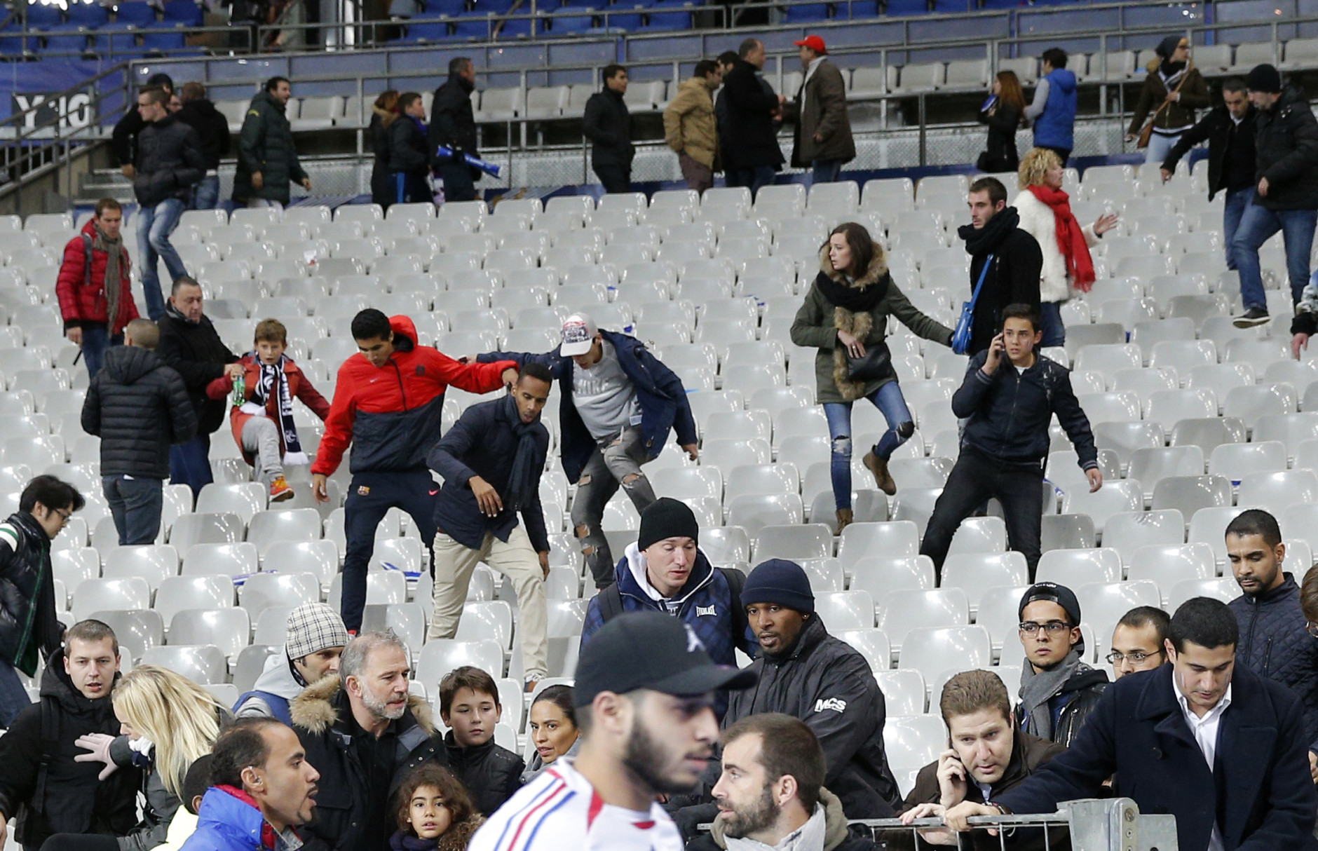 Soccer fans leave the Stade de France stadium after an international friendly soccer match in Saint Denis, outside Paris, Friday, Nov. 13, 2015. An explosion occured outside the stadium. Several dozen people were killed in a series of unprecedented attacks around Paris on Friday, French President Francois Hollande said, announcing that he was closing the country's borders and declaring a state of emergency. (AP Photo/Christophe Ena)