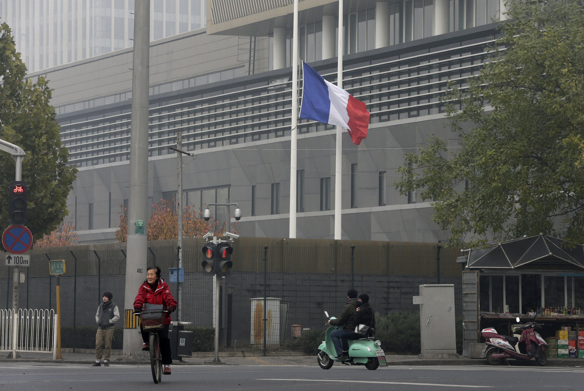 A cyclist and a motorist drive past a French national flag fluttering at half-mast to mourn for the victims killed in the Friday's attacks in Paris, France, at the French Embassy compound in Beijing, China, Saturday, Nov. 14, 2015. Foreign Ministry spokesman Hong Lei says China is "deeply shocked" by the attacks and pledged solidarity with France in combating terrorism. "Terrorism is a common challenge facing humanity. China resolutely supports France in maintaining its national security and stability and in attacking terrorism," Hong said. (AP Photo/Andy Wong)