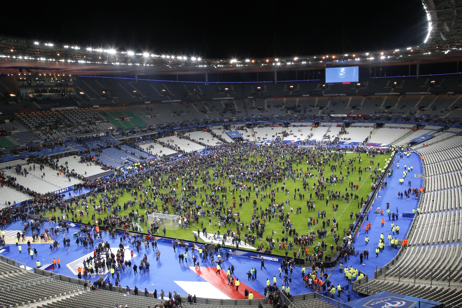 Spectators invade the pitch of the Stade de France stadium after the international friendly soccer France against Germany, Friday, Nov. 13, 2015 in Saint Denis, outside Paris. At least 35 people were killed in shootings and explosions around Paris, many of them in a popular theater where patrons were taken hostage, police and medical officials said Friday.  Two explosions were heard outside the Stade de France stadium. (AP Photo/Michel Euler)