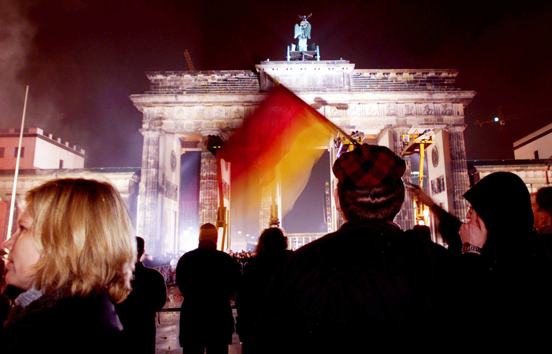 A young man waves a German flag in front of the Brandenburg gate during a party marking the tenth anniversary of the the fall of the Berlin Wall, in Berlin,Tuesday, November 9, 1999. (AP Photo/Jockel Finck)