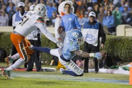 North Carolina's T.J. Logan dives for a touchdown in front of Miami's Juwon Young during the second half of an NCAA college football game, in Chapel Hill, N.C., Saturday, Nov. 14, 2015. (AP Photo/Rob Brown)