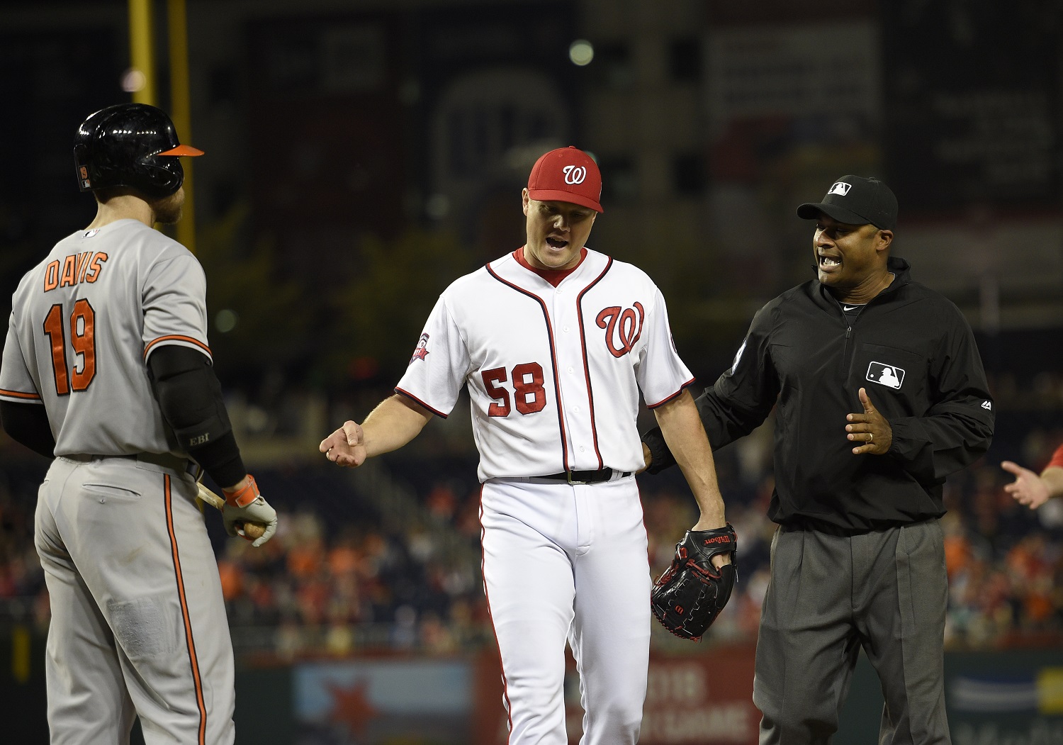 Washington Nationals relief pitcher Jonathan Papelbon (58) reacts next to and umpire Alan Porter, right, during the ninth inning of an interleague baseball game, Wednesday, Sept. 23, 2015, in Washington. Papelbon was ejected for hitting Baltimore Orioles' Manny Machado with a pitch. Also seen is Baltimore Orioles' Chris Davis. The Orioles won 4-3. (AP Photo/Nick Wass)