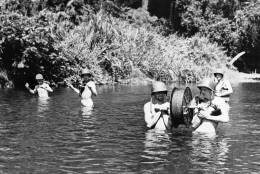 Crew of U.S. Marines fords a river on Guadalcanal, in the Solomon Islands, to lay a telephone wire on Nov. 12, 1942. They strip down to get the wire across the Longa River to provide speedy military communication. (AP Photo/Pool)