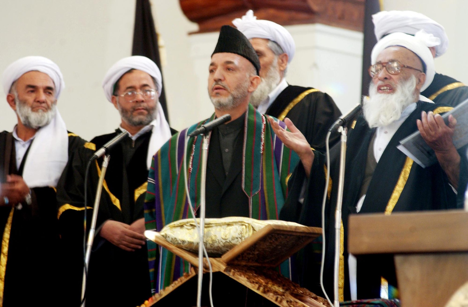 Afghan President Hamid Karzai, center, stands next to Chief Justice Fazl Hadi Shinwari, right, as he takes the oath of office during a ceremony at the Presidential Palace in Kabul Tuesday, Dec. 7, 2004. Karzai was sworn in Tuesday as Afghanistan's first popularly elected president, calling for sustained help from the international community to bolster a young democracy that sill faces the twin threats of terrorism and drugs. (AP Photo/SHAH Marai, POOL)