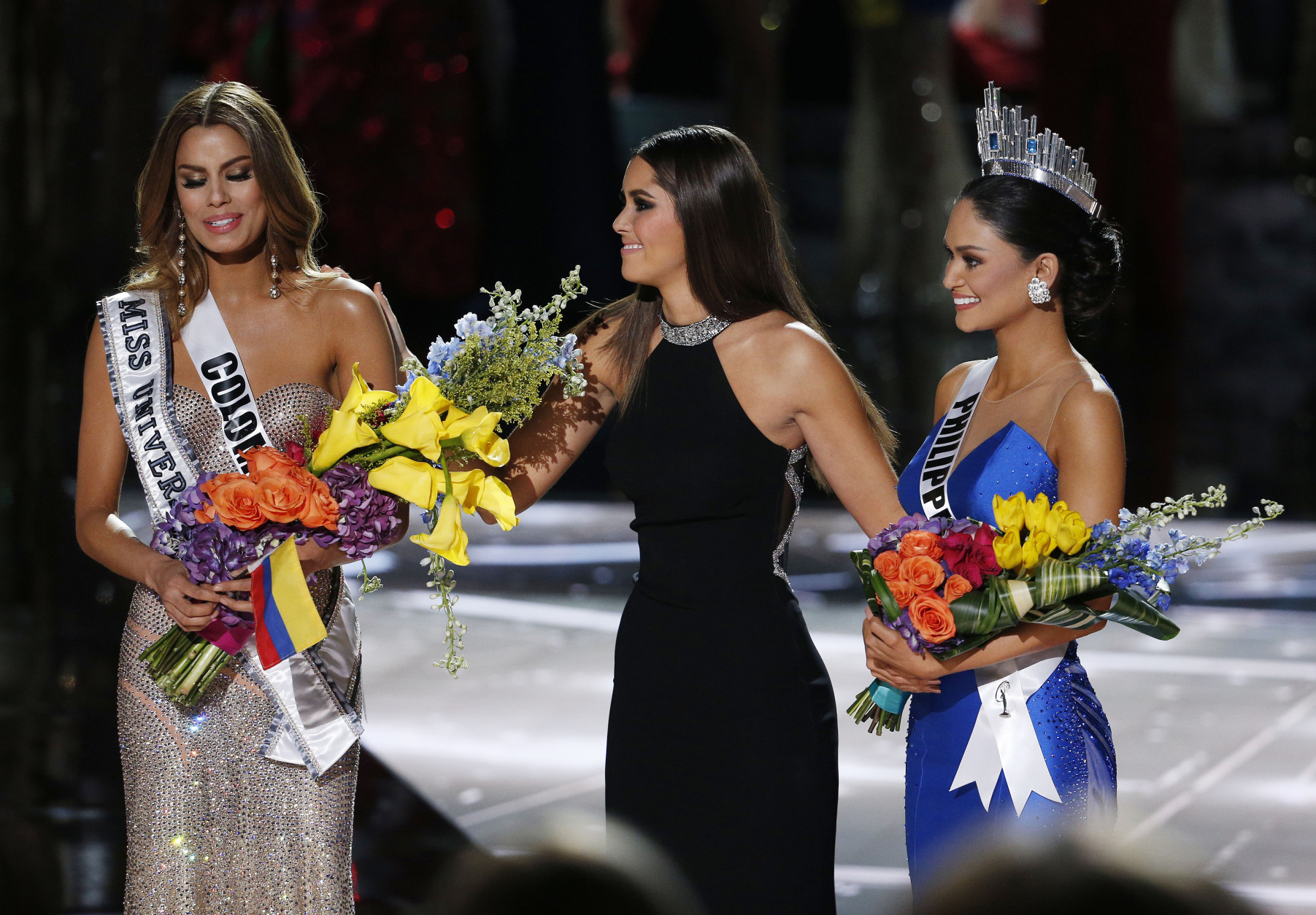 Former Miss Universe Paulina Vega, center,  takes away the flowers and sash from Miss Colombia Ariadna Gutierrez, left, before giving them to Miss Philippines Pia Alonzo Wurtzbach, right, at the Miss Universe pageant on Sunday, Dec. 20, 2015, in Las Vegas. Gutierrez was incorrectly named the winner before Wurtzbach was given the Miss Universe crown. (AP Photo/John Locher)