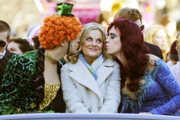 Actress Amy Poehler, center, is kissed by Jason Hellerstein, left, and Sam Clark, who are dressed in drag, as she rides in a convertible through Harvard Square in Cambridge, Mass., Thursday Jan. 29, 2015. Poehler was honored as "Woman of the Year" by the Hasty Pudding Theatricals at Harvard University. (AP Photo/Charles Krupa)