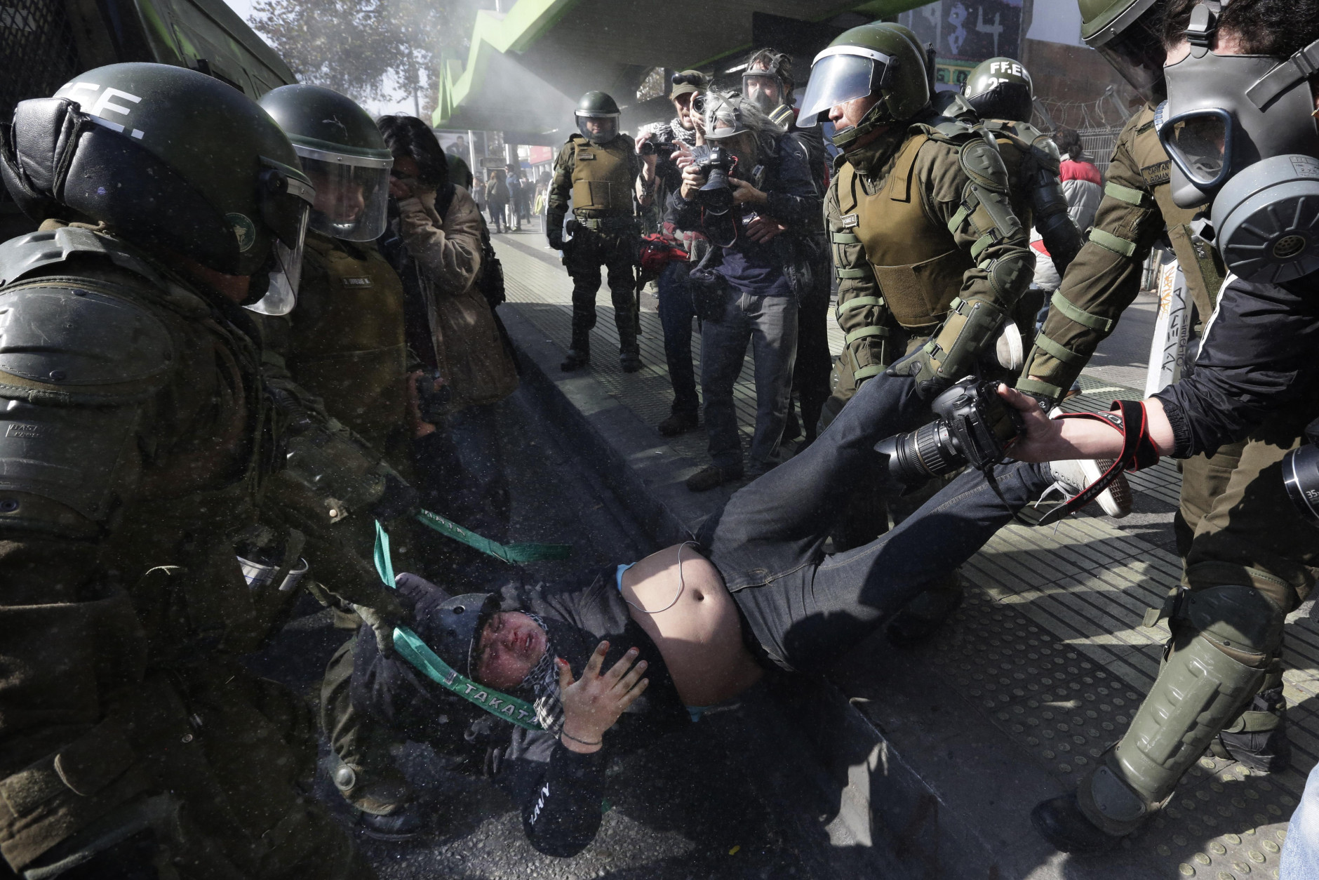 FOR USE AS DESIRED, YEAR END PHOTOS - FILE - A protester is detained by riot police at the end of a march in Santiago, Chile, Thursday, June 25, 2015. Teachers and students are asking for better salaries and participation in the government's education reform, and the march ended with some incidents between groups of hooded or masked protesters and police. (AP Photo/Jorge Saenz, File)