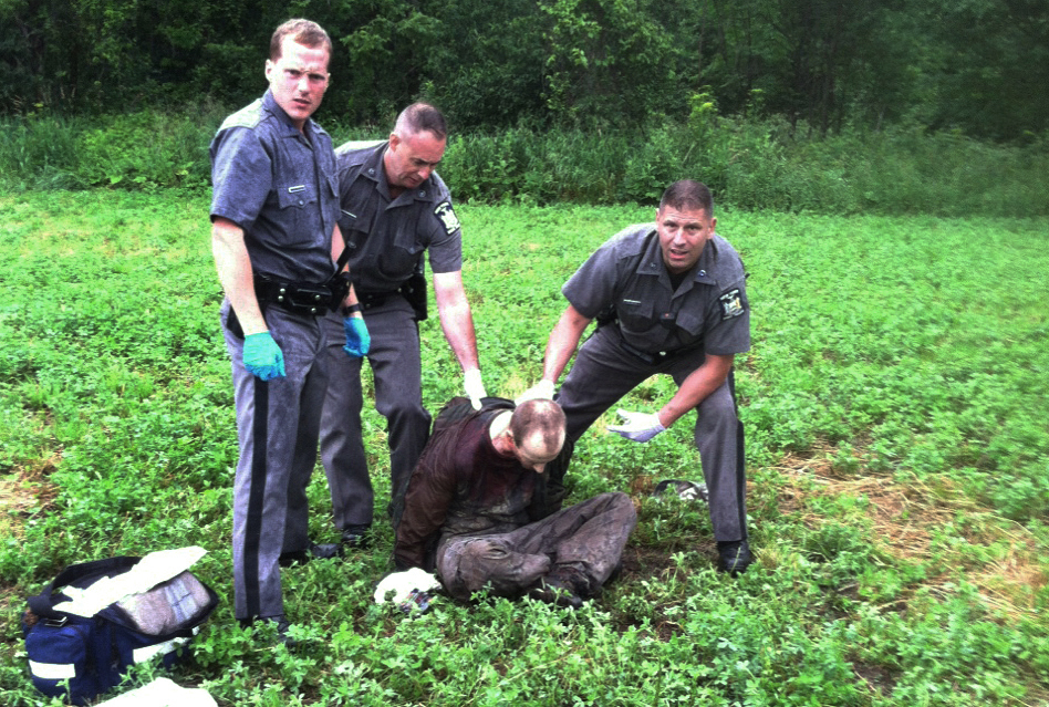 FOR USE AS DESIRED, YEAR END PHOTOS - FILE - Police stand over David Sweat after he was shot and captured near the Canadian border Sunday, June 28, 2015, in Constable, N.Y. Sweat is the second of two convicted murderers who staged a brazen escape from a maximum-security prison in northern New York. His capture came two days after his escape partner, Richard Matt, was shot and killed by authorities. (AP Photo, File)