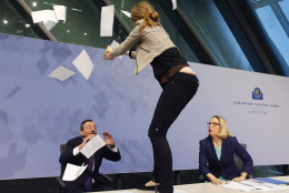 FOR USE AS DESIRED, YEAR END PHOTOS - FILE - An activist stands on the table of the podium throwing paper at ECB President Mario Draghi, left, as Christine Graeff, Director General of Communications, looks on during a press conference of the European Central Bank, ECB, in Frankfurt, Germany, Wednesday, April 15, 2015. (AP Photo/Michael Probst, File)