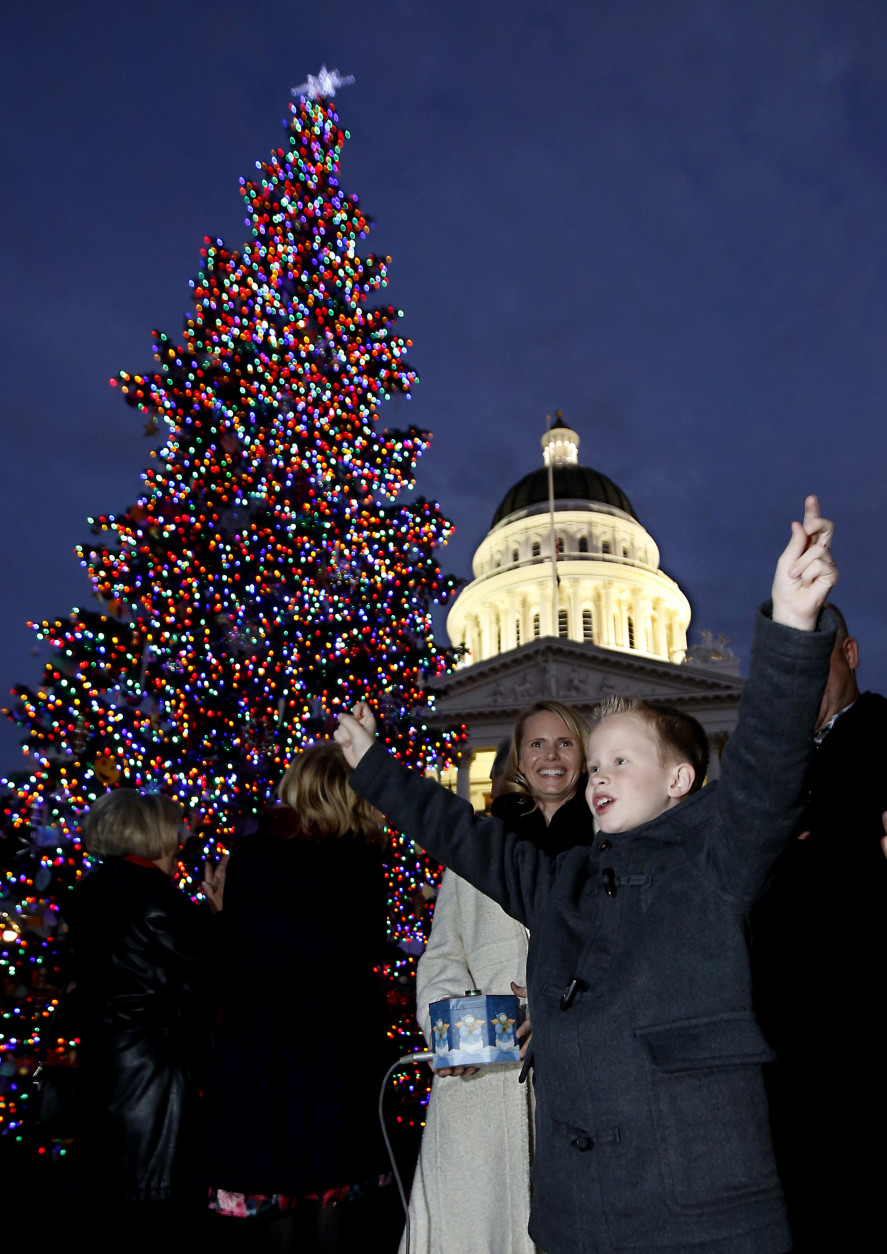 Jeffery, "J.J." Paris celebrates after lighting the Capitol Christmas tree in Sacramento, Calif., Wednesday, Dec. 2, 2015.  Gov. Jerry Brown had canceled the official lighting ceremony to honor the victims and families of the mass shooting at a San Bernardino facility that includes a center that helps people with developmental disabilities. The 61-foot tall white fir tree was is decorated with more than 10,000 LED lights and 900 hand-crafted ornaments made by children and adults with developmental disabilities who receive services from the state' development centers and nonprofit centers.(AP Photo/Rich Pedroncelli)