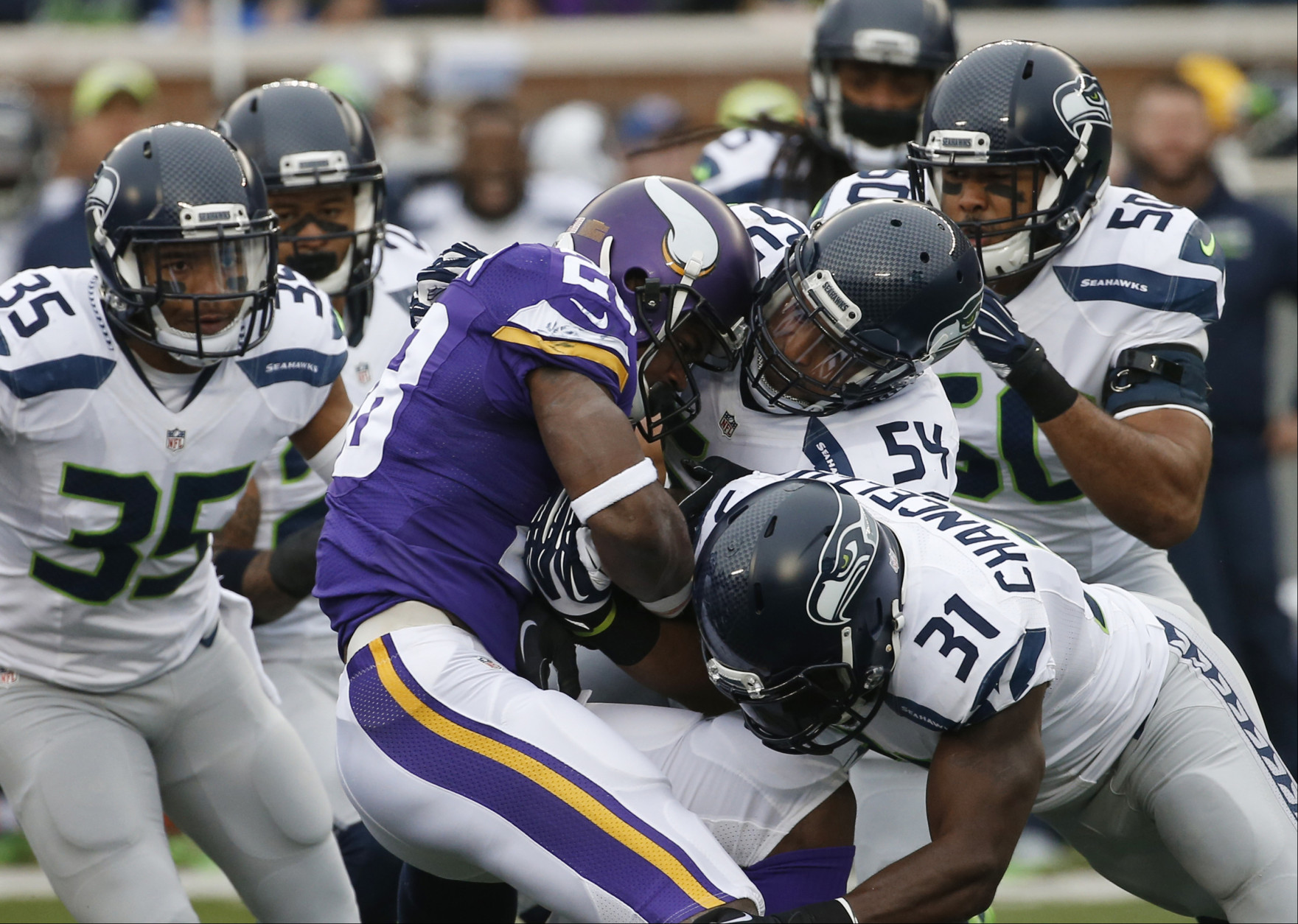 Minnesota Vikings running back Adrian Peterson (28) is stopped by Seattle Seahawks defenders including  linebacker Bobby Wagner (54) and strong safety Kam Chancellor (31)in the first half of an NFL football game Sunday, Dec. 6, 2015 in Minneapolis. (AP Photo/Ann Heisenfelt)