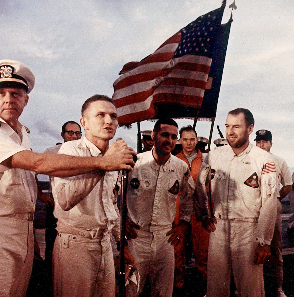 Apollo 8 Spacecraft commander Frank Borman addresses the crew of the USS Yorktown while Apollo 8 astronauts Bill Anders, center, and Jim Lovell, right, look on following a flawless lunar orbital mission and recover in the Pacific Ocean some 1,000 miles Southwest of Hawaii, Dec. 27, 1968. Navy officer at left is unidentified. (AP Photo/Four Walls Eight Windows, Nasa)