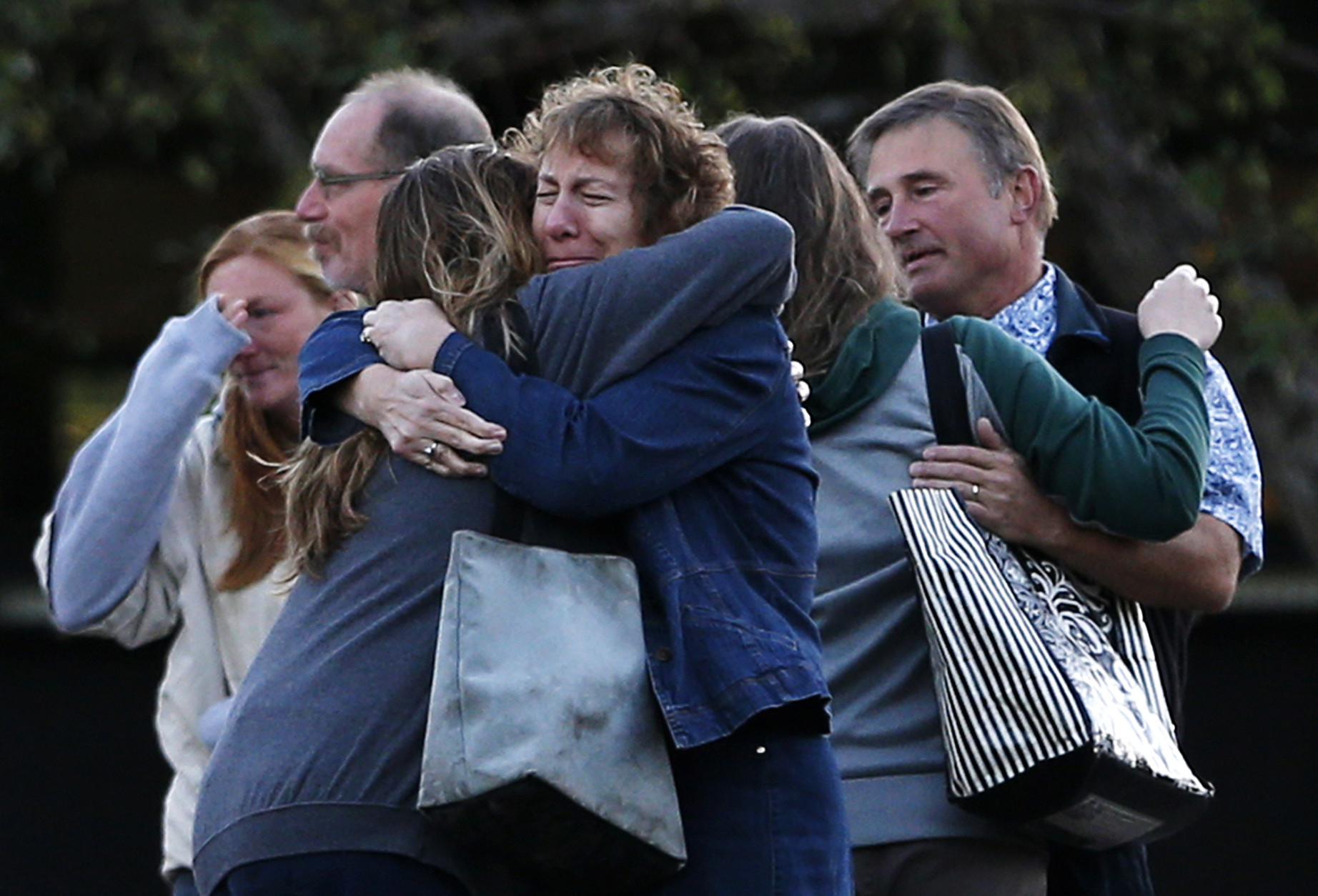 FOR USE AS DESIRED, YEAR END PHOTOS - FILE - Faculty members embrace as they are allowed to return to Umpqua Community College Monday, Oct. 5, 2015, in Roseburg, Ore. The campus reopened to faculty for the first time since Oct. 1, when armed suspect Chris Harper-Mercer killed multiple people and wounded several others before taking his own life at Snyder Hall. (AP Photo/John Locher, File)