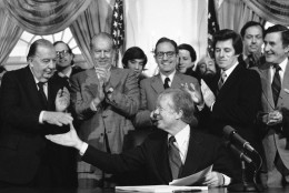 President Jimmy Carter reaches over to shake hands with Sen. Randolph Jennings, D-W.Va., left, after signing the environmental Superfund legislation in the Cabinet Room of the White House in Washington on Dec. 11, 1980. Behind Carter from left: Jennings; Sen. Robert Stafford, R-Vt., applauding; Rep. George Mitchell, D-ME., behind Carter; Rep. Al Gore, D-TN; Rep. James J. Florio, D-N.J., also applauding; Sen. Bill Bradley, D-N.J., behind Florio; and Sen. John H. Chafee, R-R.I., far right. (AP Photo/Dennis Cook)