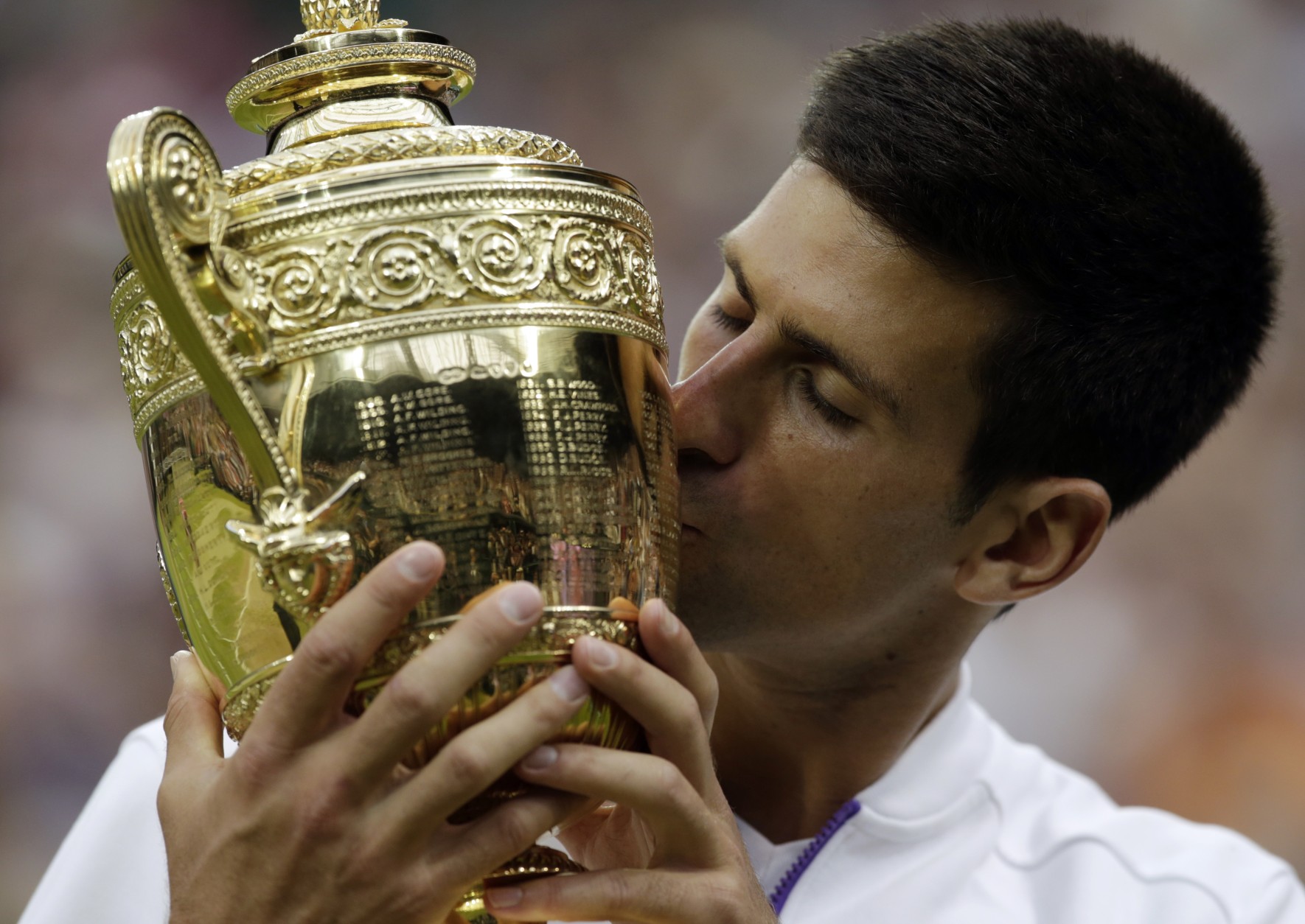 Novak Djokovic of Serbia kisses the trophy after winning the men's singles final against Roger Federer of Switzerland at the All England Lawn Tennis Championships in Wimbledon, London, Sunday July 12, 2015. Djokovic won the match 7-6, 6-7, 6-4, 6-3. (AP Photo/Alastair Grant)