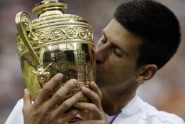 Novak Djokovic of Serbia kisses the trophy after winning the men's singles final against Roger Federer of Switzerland at the All England Lawn Tennis Championships in Wimbledon, London, Sunday July 12, 2015. Djokovic won the match 7-6, 6-7, 6-4, 6-3. (AP Photo/Alastair Grant)