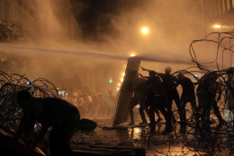 FOR USE AS DESIRED, YEAR END PHOTOS - FILE - Lebanese activists hold up a makeshift shield as they are sprayed by riot police using water cannons during a protest against the ongoing trash crisis, in downtown Beirut, Lebanon, Sunday, Aug. 23, 2015. Lebanese riot police fired several rounds of tear gas and water cannons for the second consecutive day in downtown Beirut as they battled protesters with batons and stones _ a marked escalation of mass demonstrations against an ongoing trash crisis. (AP Photo/Hassan Ammar, File)