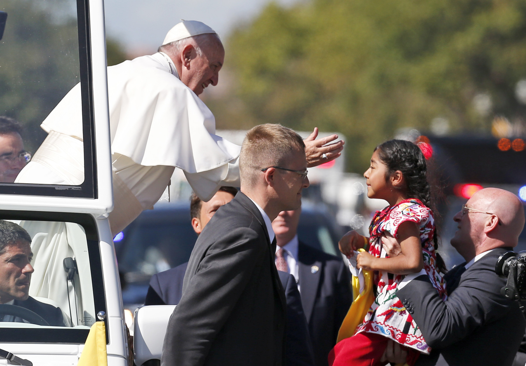 Pope Francis reaches from the popemobile for a child that is brought to him, during a parade in Washington, Wednesday, Sept. 23, 2015. (AP Photo/Alex Brandon, Pool)