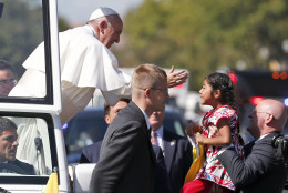 Pope Francis reaches from the popemobile for a child that is brought to him, during a parade in Washington, Wednesday, Sept. 23, 2015. (AP Photo/Alex Brandon, Pool)