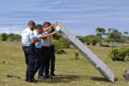 FOR USE AS DESIRED, YEAR END PHOTOS - FILE - French police officers inspect a piece of debris from a plane in Saint-Andre, Reunion Island on July 29, 2015. It was later confirmed the wing flap found on an island in the western Indian Ocean was part of Malaysia Airlines Flight 370, a Boeing 777 that had disappeared 17 months ago.  (AP Photo/Lucas Marie, File)