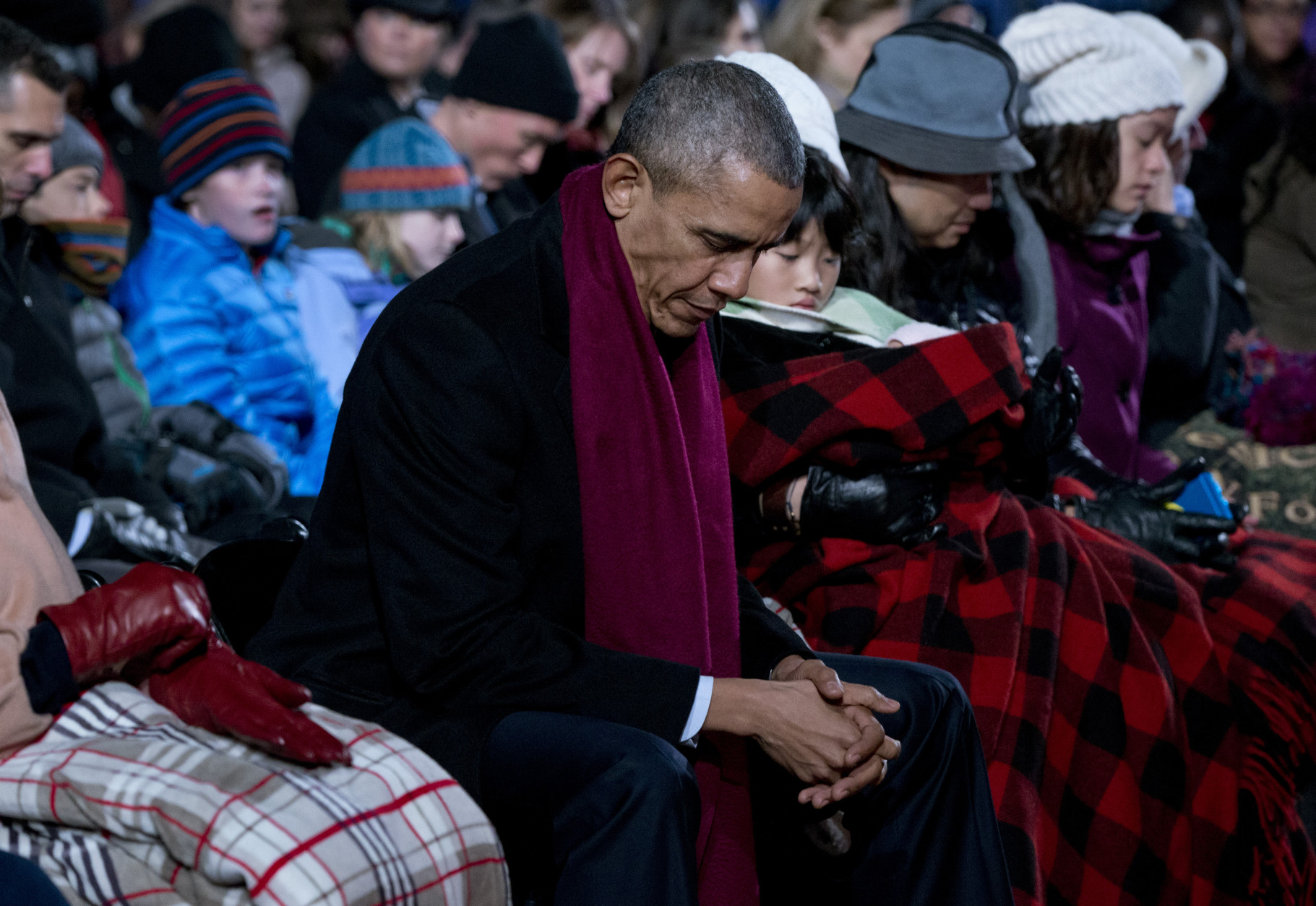 President Barack Obama bows his head in prayer during the National Christmas Tree Lighting ceremony at the Ellipse in Washington, Thursday, Dec. 3, 2015. (AP Photo/Carolyn Kaster)