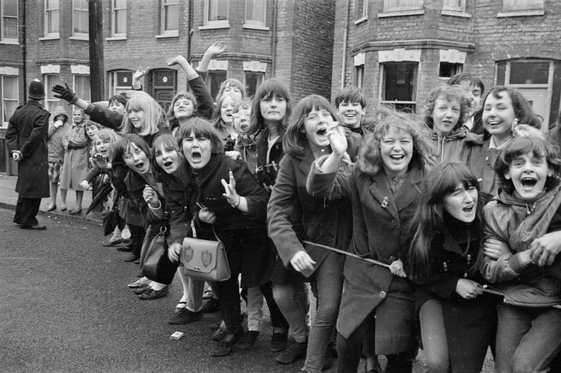 15th March 1965:  British police hold back excited young Beatles fans hoping for a glimpse of their musical heroes during the filming of the musical 'Help', on location in London.  (Photo by Stan Meagher/Express/Getty Images)