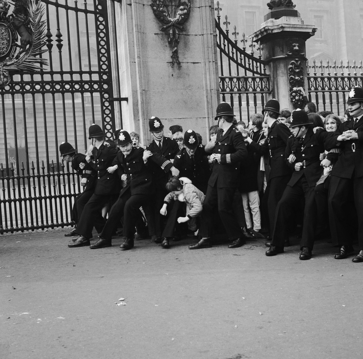 Police hold back a mass of young Beatles fans outside Buckingham Palace, London, where the pop group received MBE's, 26th October 1965. (Photo by Ted West/Roger Jackson/Central Press/Hulton Archive/Getty Images)