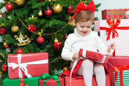happy child opens Christmas gifts near  tree