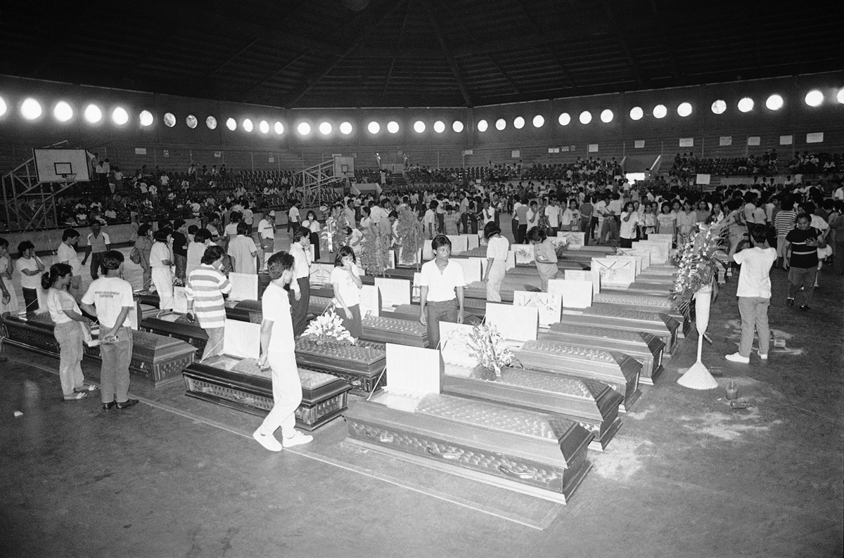 Relatives crowd at coffins of victims of the ill-fated passenger ship M/V Dona Paz which collided with a fuel tanker M/T Victor December 20 killing at least 1500 passengers. Some 50 coffins were brought to Manila's Rizal Memorial Coliseum Dec. 28, 1987 because funeral parlors cannot accommodate the increasing number of dead bodies recovered 8 days since the worst sea tragedy of the century. (AP Photo/Willie Salenga)