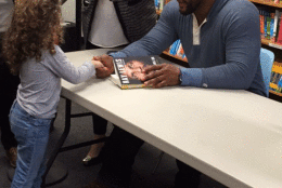 Ray Lewis signs a girl's book in D.C. Tuesday. (WTOP/Molly Welton)