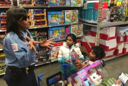 Officer Myra Jordan talks to children during the “Shop with a Cop!” event, using American Sign Language. The little boy pictured here wrapped his arms around Jordan’s legs, giving her a long hug. He said he did it to say, “Thank you, thank you.”  (WTOP/Kristi King)