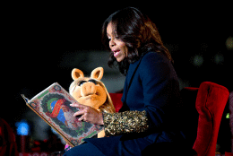 First lady Michelle Obama and Miss Piggy read "The Night Before Christmas" to children on stage during the National Christmas Tree Lighting ceremony at the Ellipse in Washington, Thursday, Dec. 3, 2015. (AP Photo/Carolyn Kaster)