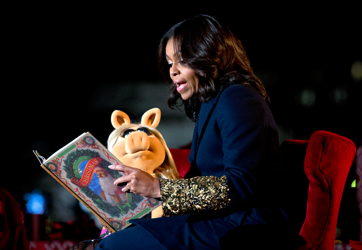 First lady Michelle Obama and Miss Piggy read "The Night Before Christmas" to children on stage during the National Christmas Tree Lighting ceremony at the Ellipse in Washington, Thursday, Dec. 3, 2015. (AP Photo/Carolyn Kaster)