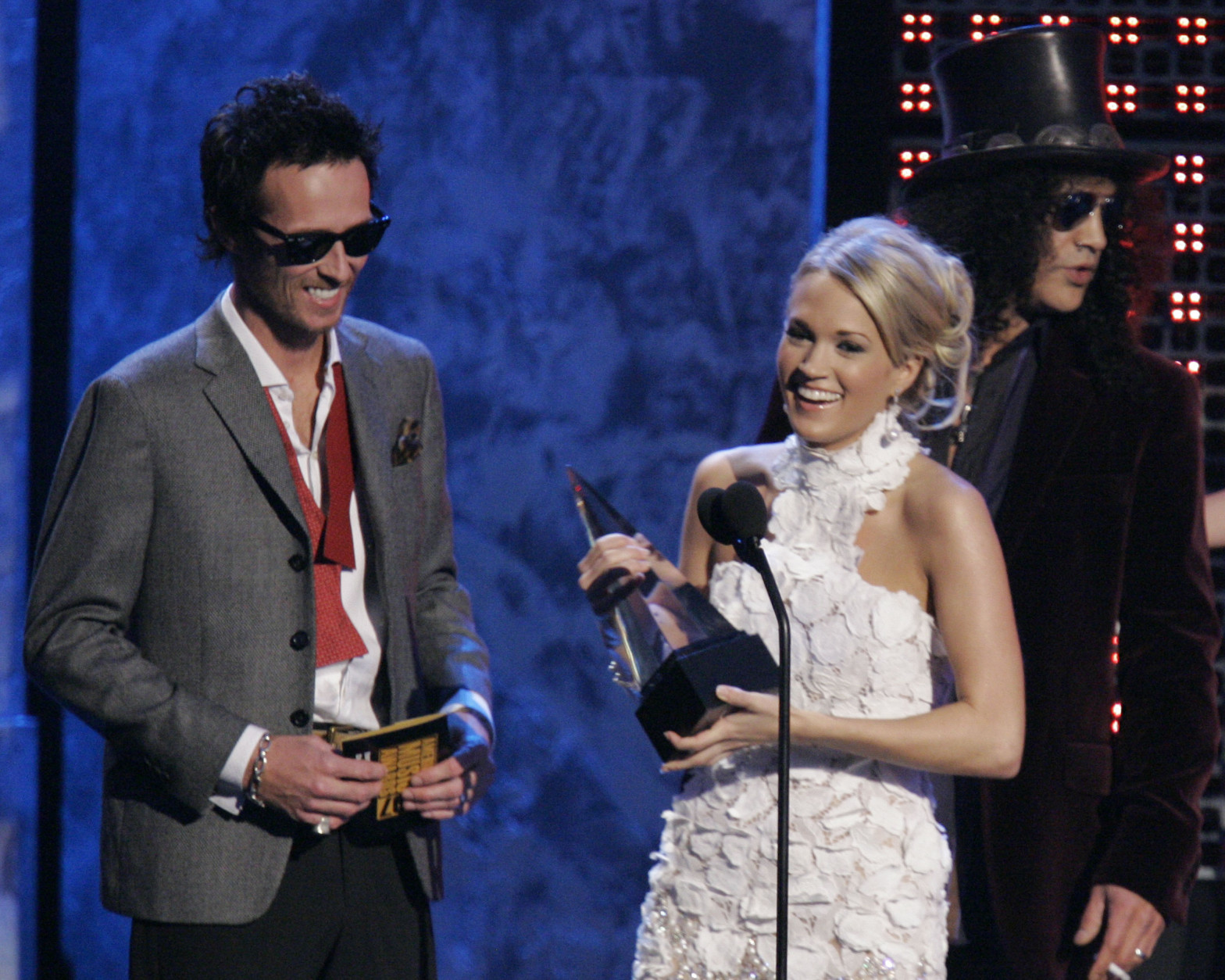 Scott Weiland, left, presents Carrie Underwood with the T-Mobile text in award in the background at the American Music Awards in Los Angeles on Sunday, Nov. 18, 2007. Slash is in the background. (AP Photo/Mark J. Terrill)