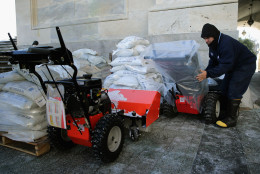 Stone Mason Medaro Romero covers gas powered snow sweepers in plastic bags in preparation for a coming winter storm outside the U.S. Capitol January 21, 2016 in Washington, DC. One inch of snowfall delayed school openings in the greater Washington, DC, area on Thursday as people along the Easter Seaboard prepare for a blizzard to arrive within the next 24 hours.  (Photo by Chip Somodevilla/Getty Images)