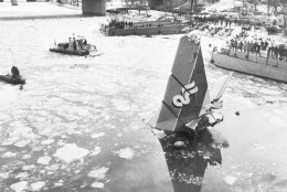 The tail of the Air Florida jet that crashed into the Potomac River in Washington, D.C.,  is hoisted from the water by a crane, Jan. 18, 1982, during salvage efforts. The 14th Street Bridge that the plane hit while taking off from National Airport is pictured in background. (AP Photo)