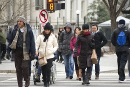 Pedestrians cross 15th Street in downtown Washington near the White House, Friday, Jan. 22, 2016, as the Nations Capital hunkers down in preparation for a major snowstorm expected to begin later today. Food and supplies vanished from store shelves, five states and the District of Columbia declared states of emergency ahead of the slow-moving system. (AP Photo/Pablo Martinez Monsivais)