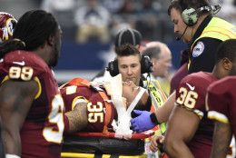Washington Redskins' Dashaun Phillips (35) is carted off the field by first responders as Ricky Jean Francois (99) watches in the first half of an NFL football game against the Dallas Cowboys, Sunday, Jan. 3, 2016, in Arlington, Texas. Phillips was injured while helping stop Cowboys running back Darren McFadden on a running play. (AP Photo/Michael Ainsworth)
