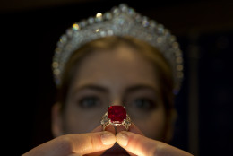 An employee of Sotheby's auction house holds up the 'Sunrise Ruby' ring, a cushion shaped Myanmar ruby of some 25.59 carats of pigeon blood colour during a photocall in London, Wednesday, April 8, 2015. The ring will be sold at auction on May in Geneva, Switzerland with an estimated price of US$ 12-18 million. (AP Photo/Alastair Grant)