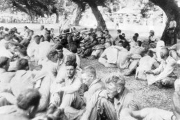 While a Japanese soldier stands guard, center, with fixed bayonet, these American soldiers captured on Bataan and Corregidor, pause to rest. According to the Marine Corps caption, this photo was taken during the "March of Death" on Luzon in April 1942 and photo was stolen by Filipinos from the Japanese. (AP photo)