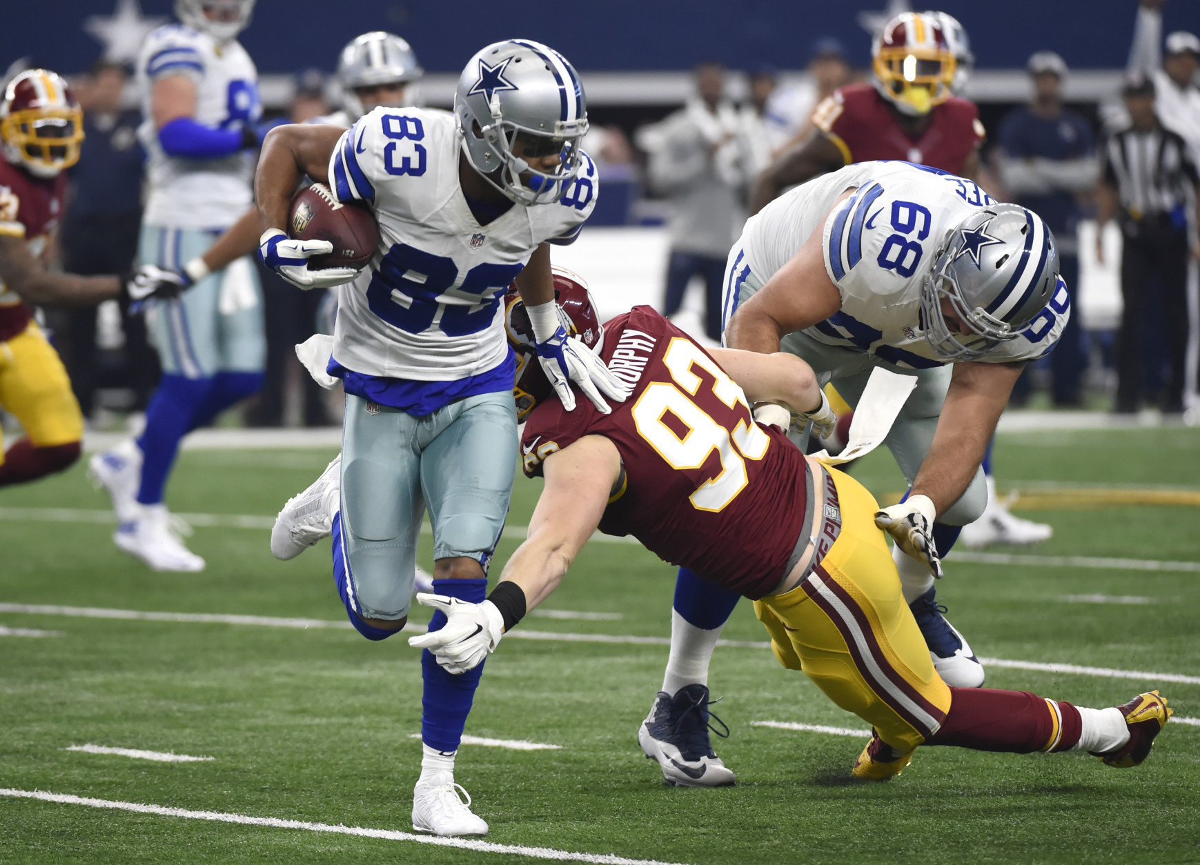 Dallas Cowboys wide receiver Terrance Williams (83) fights off a tackle-attempt by Washington Redskins outside linebacker Trent Murphy (93) with help from teammate Doug Free (68) while gaining yardage after catching a pass in the first half of an NFL football game, Sunday, Jan. 3, 2016, in Arlington, Texas. (AP Photo/Michael Ainsworth)