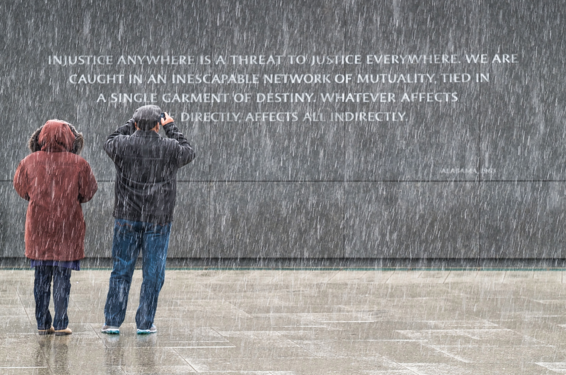 Visitors at the Martin Luther King, Jr. Memorial in Washington stop to photograph the quotes etched into the memorial's back wall while it snows on Sunday, Jan. 17, 2016.  (AP Photo/J. David Ake)