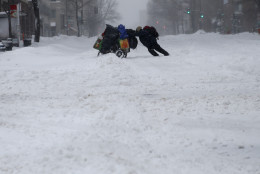 A homeless man pushes a cart with his belongings across 13th Street in downtown Washington, Saturday, Jan. 23, 2016. Millions of people awoke Saturday to heavy snow outside their doorsteps, strong winds that threatened to increase through the weekend, and largely empty roads as residents from the South to the Northeast heeded warnings to hunker down inside while a mammoth storm barreled across a large swath of the country. (AP Photo/Gerald Herbert)