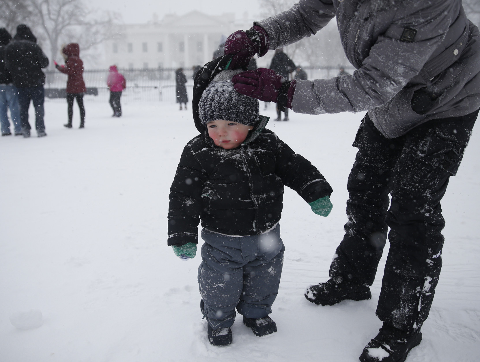 Meghan Murphy of Crofton, Md., adjusts the hat of her son Chase Murphy,  1, during heavy snowfall in front of the White House in Washington on Saturday, Jan. 23, 2016.  A blizzard with hurricane-force winds brought much of the East Coast to a standstill Saturday, dumping as much as 3 feet of snow, stranding tens of thousands of travelers and shutting down the nation's capital and its largest city.(AP Photo/Gerald Herbert)