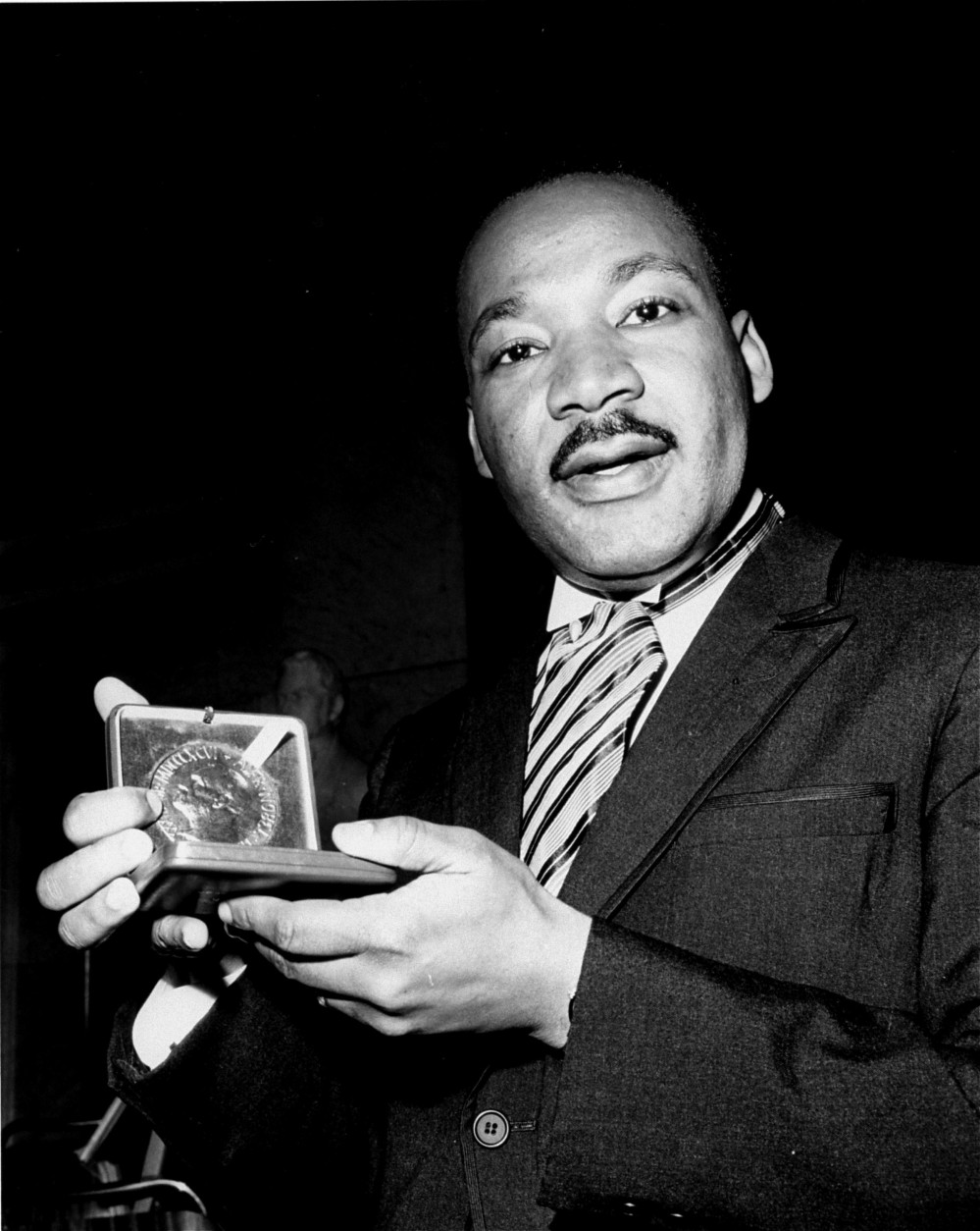 Dr. Martin Luther King, Jr. displays his 1964 Nobel Peace Prize medal in Oslo, Norway, December 10, 1964.  The 35-year-old Dr. King was honored for promoting the principle of non-violence in the civil rights movement.  (AP Photo)